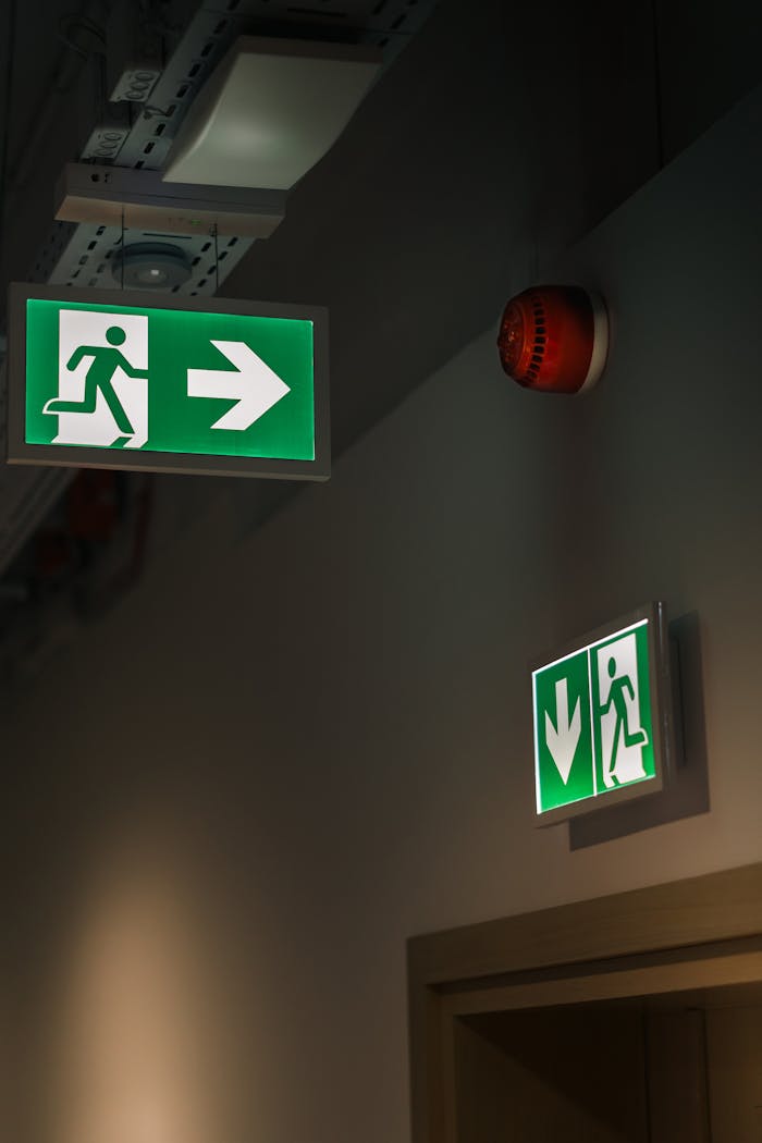 Illuminated green emergency exit signs in a building hallway, ensuring safety and guidance.