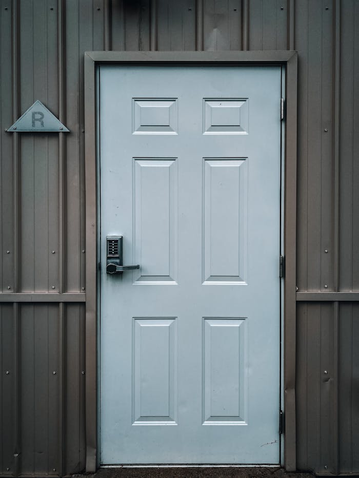 A sleek steel door with a keypad lock on a metallic siding exterior, showcasing industrial design.