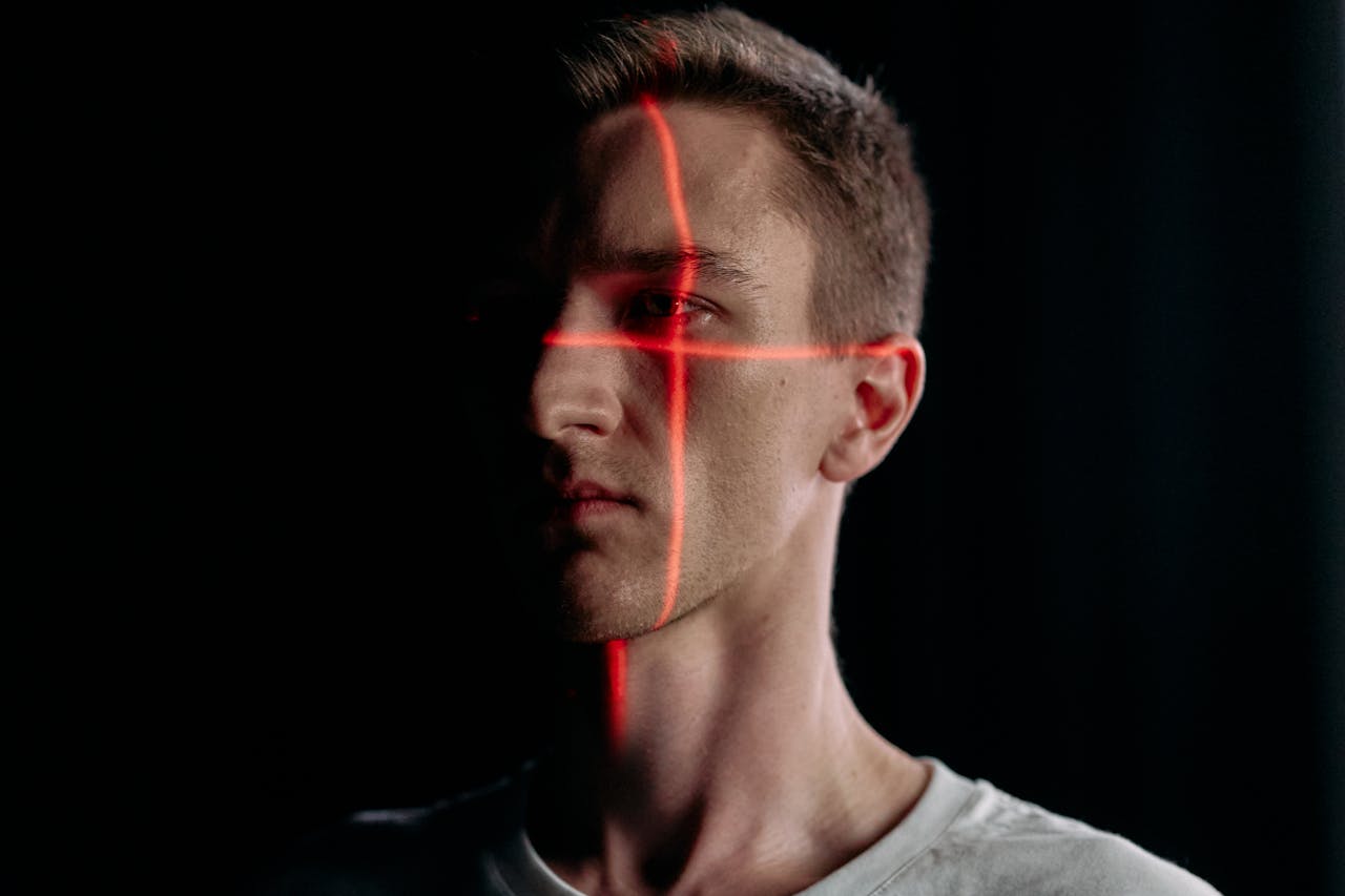 Studio portrait of a man with a laser grid pattern for facial recognition on a black background.